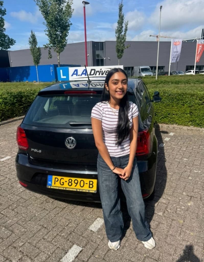 Celine met haar rijbewijs naast de lesauto